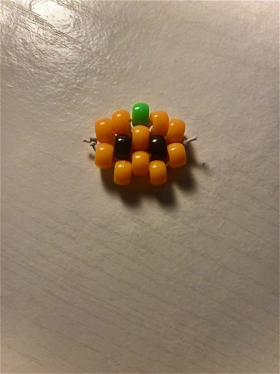 Small beaded pumpkin charm with a green stem